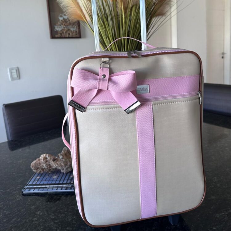mala de rodinha em um dourado light com faixa rosa bebê